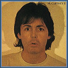 a yellow-tinted photograph of Paul McCartney at shoulder-length giving a confused or ambivalent expression.