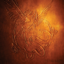 A symbol containing a mockingjay imprinted on a golden background