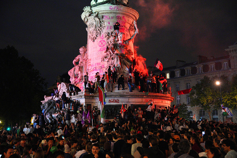 PARIS, FRANCE - JULY 07: Demonstrators climb on the Monument a la Republique during a protest following the legislative election results on July 7, 2024 in Paris, France. The right-wing National Rally party came in third place after having been expected to have a strong showing in the second round of France's parliamentary election, which was called by the French president last month after his party performed poorly in the European election. (Photo by Carl Court/Getty Images)