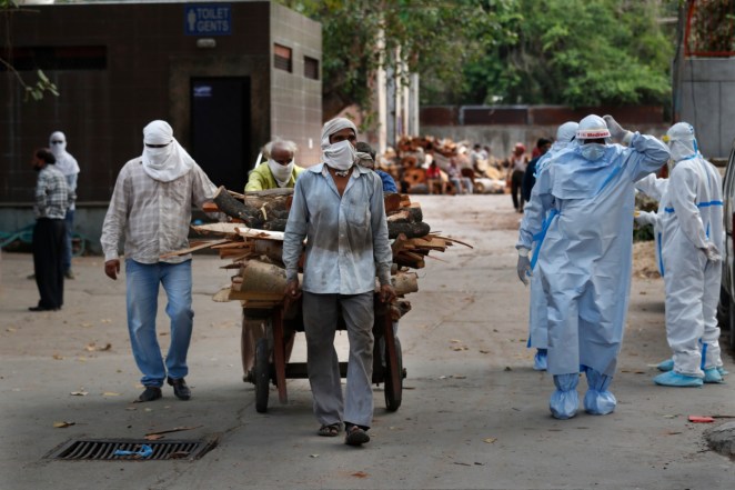 Workers push a handcart carrying wood for the funeral pyre of victims of coronavirus, at a crematorium in New Delhi, India.