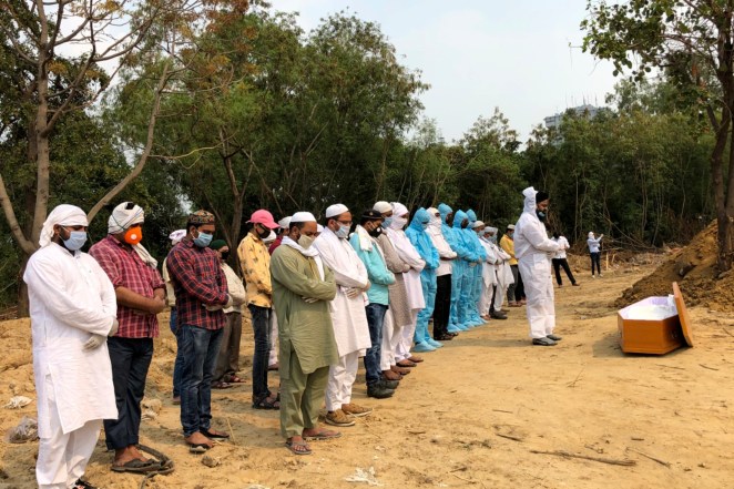 Mourners in personal protective gear offer prayers before the burial of their relative who died of coronavirus at a cemetery in New Delhi, India.