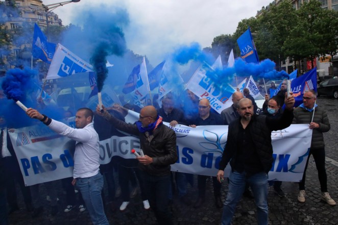 French police unionists fire blue flares as they demonstrate with a banner reading" No police, no peace" down the Champs-Elysee avenue in Paris, France. 