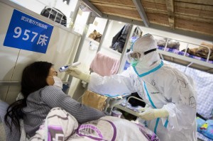 Medical staff take the temperature of a patient at a makeshift hospital in Wuhan, China.