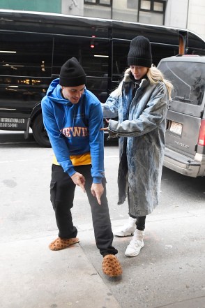 Justin Bieber proudly shows off his designer slippers while wife Hailey Baldwin keeps him moving.