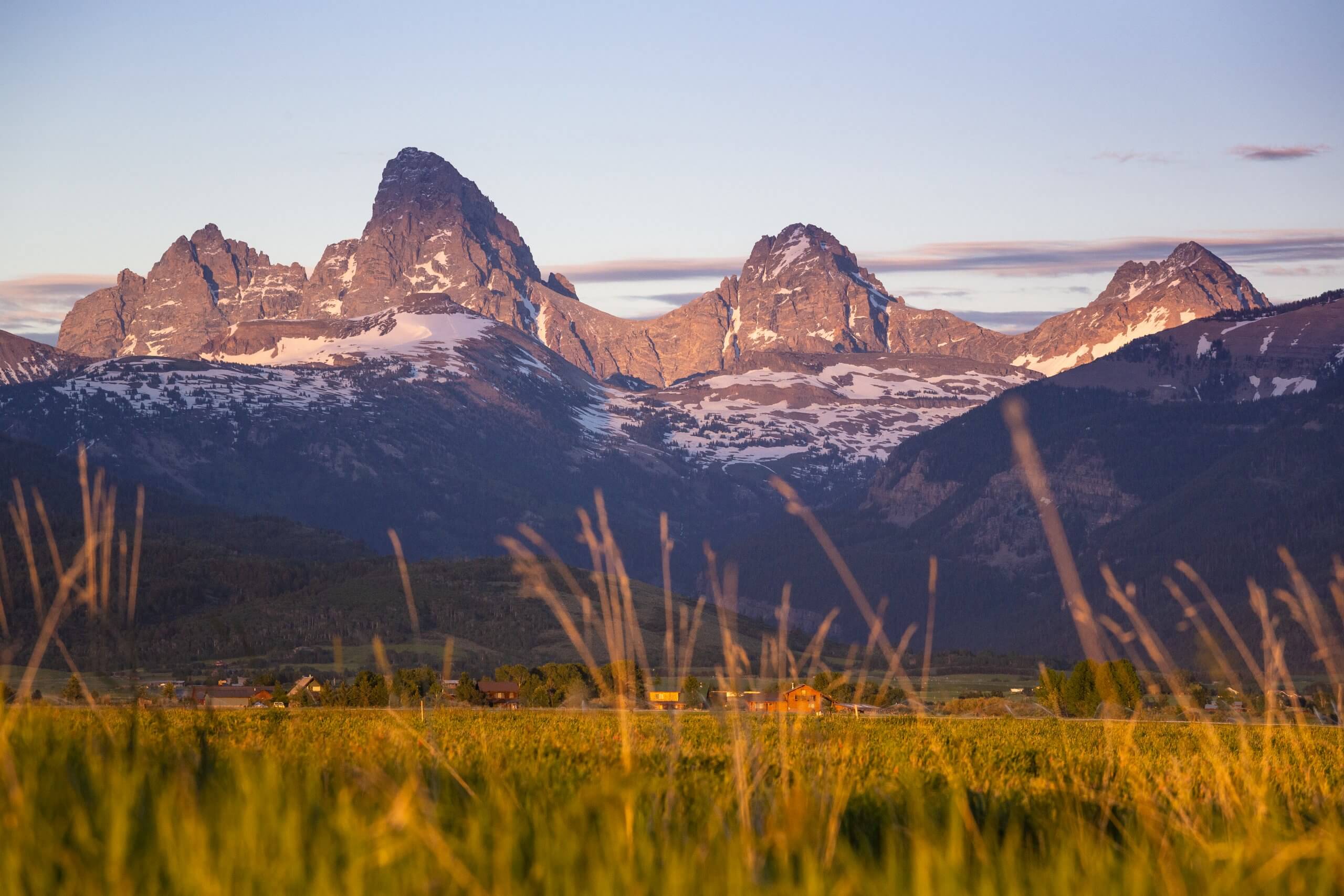 A sunset across a large Teton Mountain range landscape.