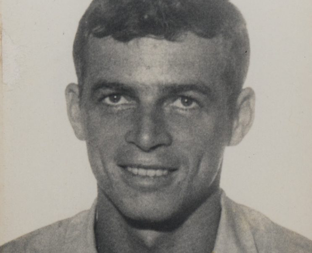 Fotografia em preto e branco de Stuart Angel, jovem branco, de cabelos curtos e lisos. Na foto ele aparece vestindo uma camisa de cor clara e sorrindo para a câmera.