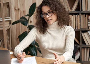 Young Latin female professional taking an online class and looking at laptop monitor