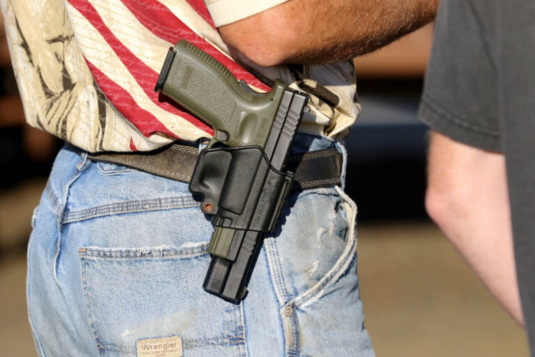 In this Oct. 9, 2015 file photo, Michael Johnson wears a firearm as he waits outside of Roseburg Municipal Airport in Roseburg, Ore.