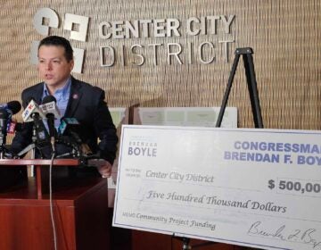 Brendan Boyle speaking a podium, with a giant check