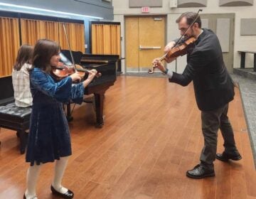 Serban Petrescu and Tatyana Roytshteyn’s younger daughter, Alexandra (9) in this photo at a studio recital, with their older daughter Beatrice playing the piano at Widener University. (Courtesy of Serban Petrescu and Tatyana Roytshteyn)