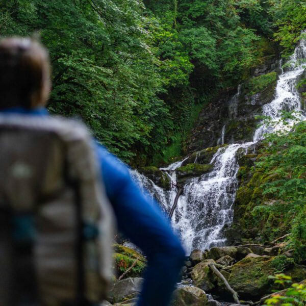 Hiker admiring Torc Waterfall in Killarney, Co. Kerry, Ireland