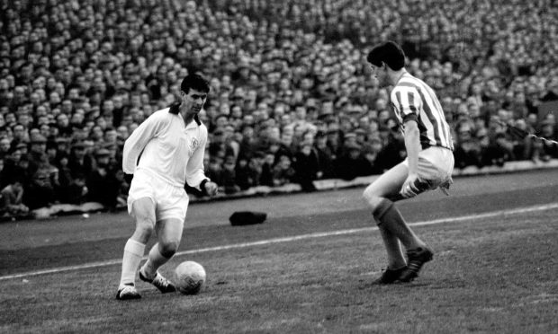 Gordon Smith goes up against Jim Baxter of Rangers, with the crowd looking on