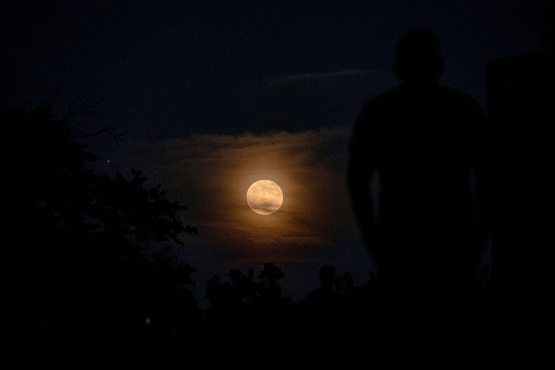 Onlookers watch as the full "Strawberry moon" rises in Arlington, Virginia, on June 14, 2022. (Photo by Stefani Reynolds / AFP) (Photo by STEFANI REYNOLDS/AFP via Getty Images)