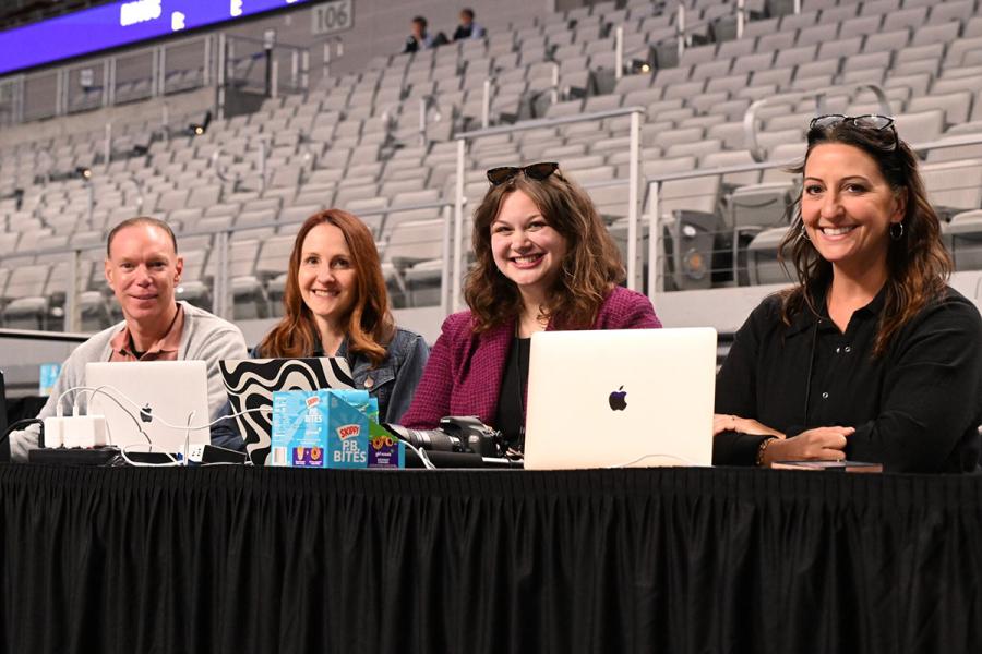 Journalism Student Della Fowler sitting with three other people at table in gymnastics meet