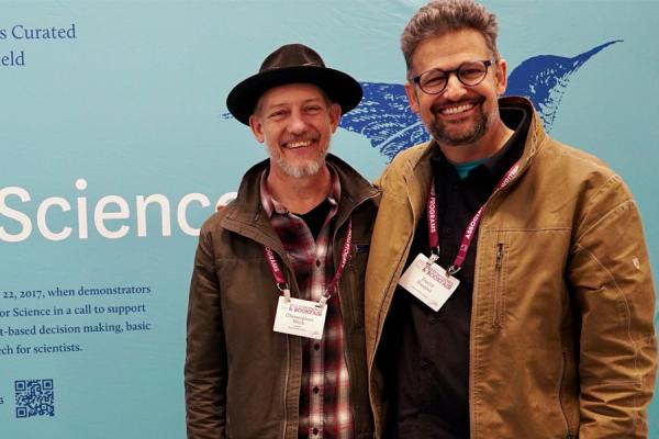 Chris Wick (left) and David Hassler (right) stand in front of the Wick Poetry Center’s Poets for Science exhibition at the Association of Writers & Writing Programs’ 2023 Conference and Bookfair.