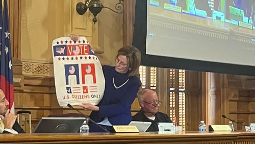 State Election Board member Janice Johnston holds up a sign encouraging only U.S. citizens to vote during a State Election Board meeting Wednesday at the Georgia Capitol in Atlanta. The board voted 3-1 to email the sign to all 159 counties, encouraging election officials to post the sign at polling locations and election offices. Voting rights groups say they’re concerned the sign could discourage immigrants who have become citizens from registering to vote in a state that already has stringent voting laws.