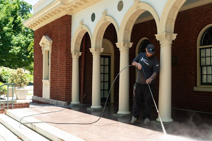 Landscape maintenance technician Josh Conley washes the exterior of the Piedmont Park Visitors' Center in Atlanta on Tuesday, June 25, 2024. (Seeger Gray / AJC)