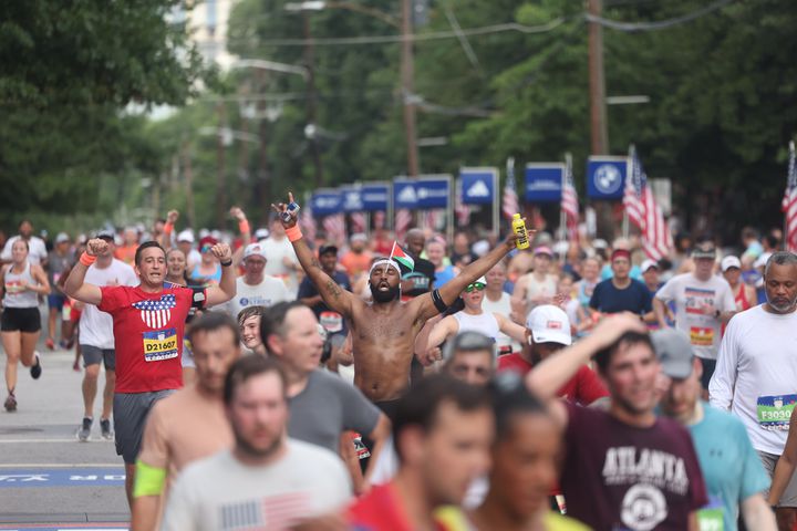 Runners celebrate at the finish of the 55th running of the Atlanta Journal-Constitution Peachtree Road Race in Atlanta on Thursday, July 4, 2024.   (Jason Getz / AJC)