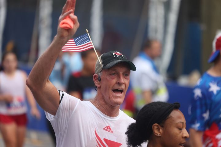 Runners celebrate at the finish of the 55th running of the Atlanta Journal-Constitution Peachtree Road Race in Atlanta on Thursday, July 4, 2024.   (Jason Getz / AJC)