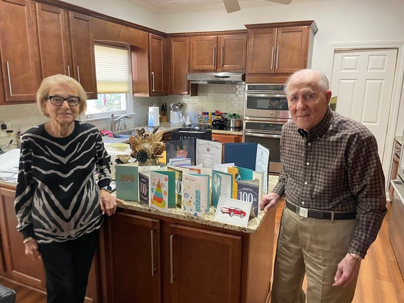 Hilbert and Betty Ann Margol in front of cards celebrating his 100th birthday. The couple has been married 75 years.