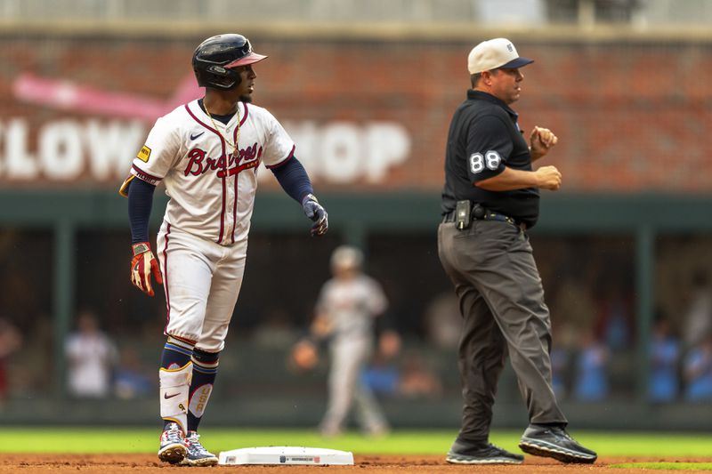 Atlanta Braves' Ozzie Albies, left, looks past an umpire, right, to Braves first base coach Tom Goodwin (not shown) in the first inning of a baseball game against the San Francisco Giants, Thursday, July 4, 2024, in Atlanta. (AP Photo/Jason Allen)