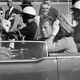 FILE - President John F. Kennedy waves from his car in a motorcade approximately one minute before he was shot, Nov. 22, 1963, in Dallas. Riding with President Kennedy are first lady Jacqueline Kennedy, right, Nellie Connally, second from left, and her husband, Texas Gov. John Connally, far left. (AP Photo/Jim Altgens, File)