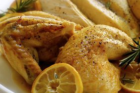 close up view of Butterflied Roast Chicken garnished with Lemon and Rosemary on a platter