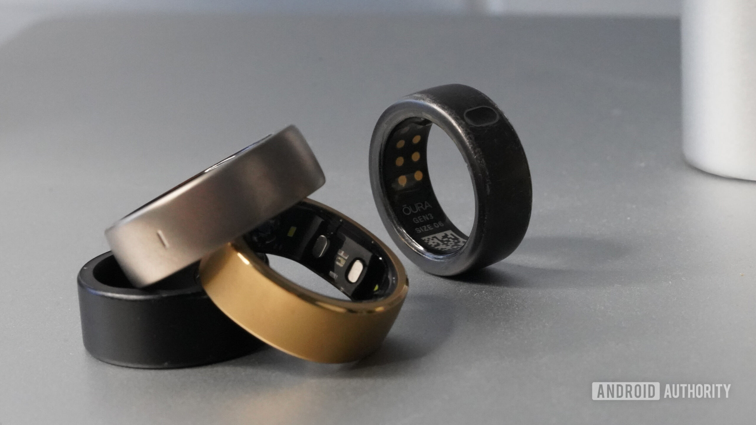 An Oura Ring 3 rests slightly behind a pil of alternative smart rings.