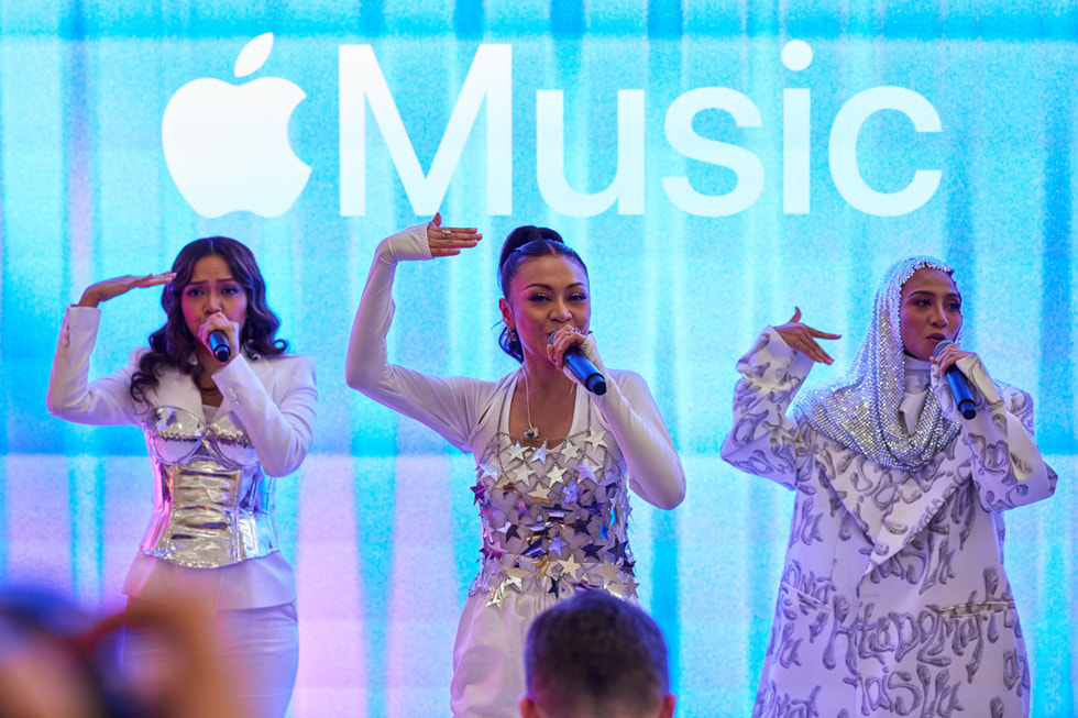 Hình ảnh cận cảnh màn trình diễn của De Fam, với logo Apple Music trên màn hình phía sau ban nhạc. 