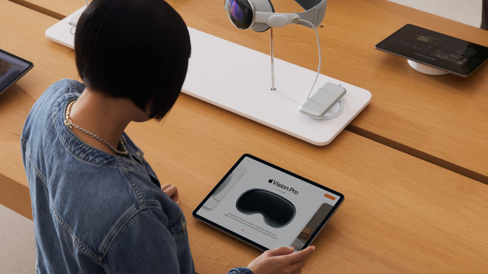 Apple StoreでiPadに表示されているApple Vision Proを見ているお客様。