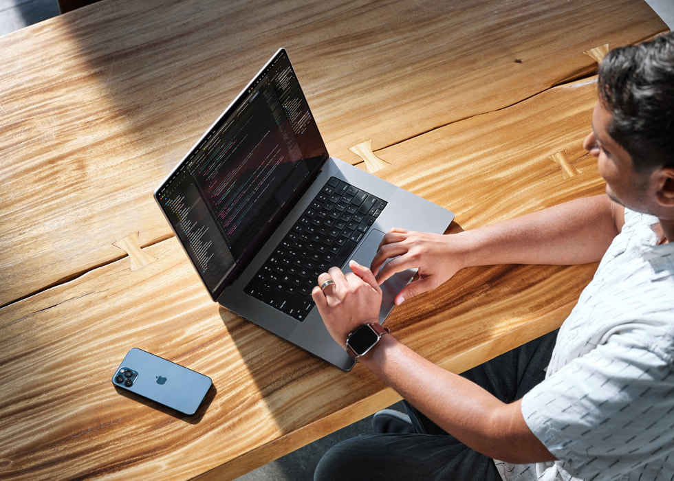 An overhead photo shows Swupnil Sahai working at a desk with MacBook Pro, and iPhone off to the side.