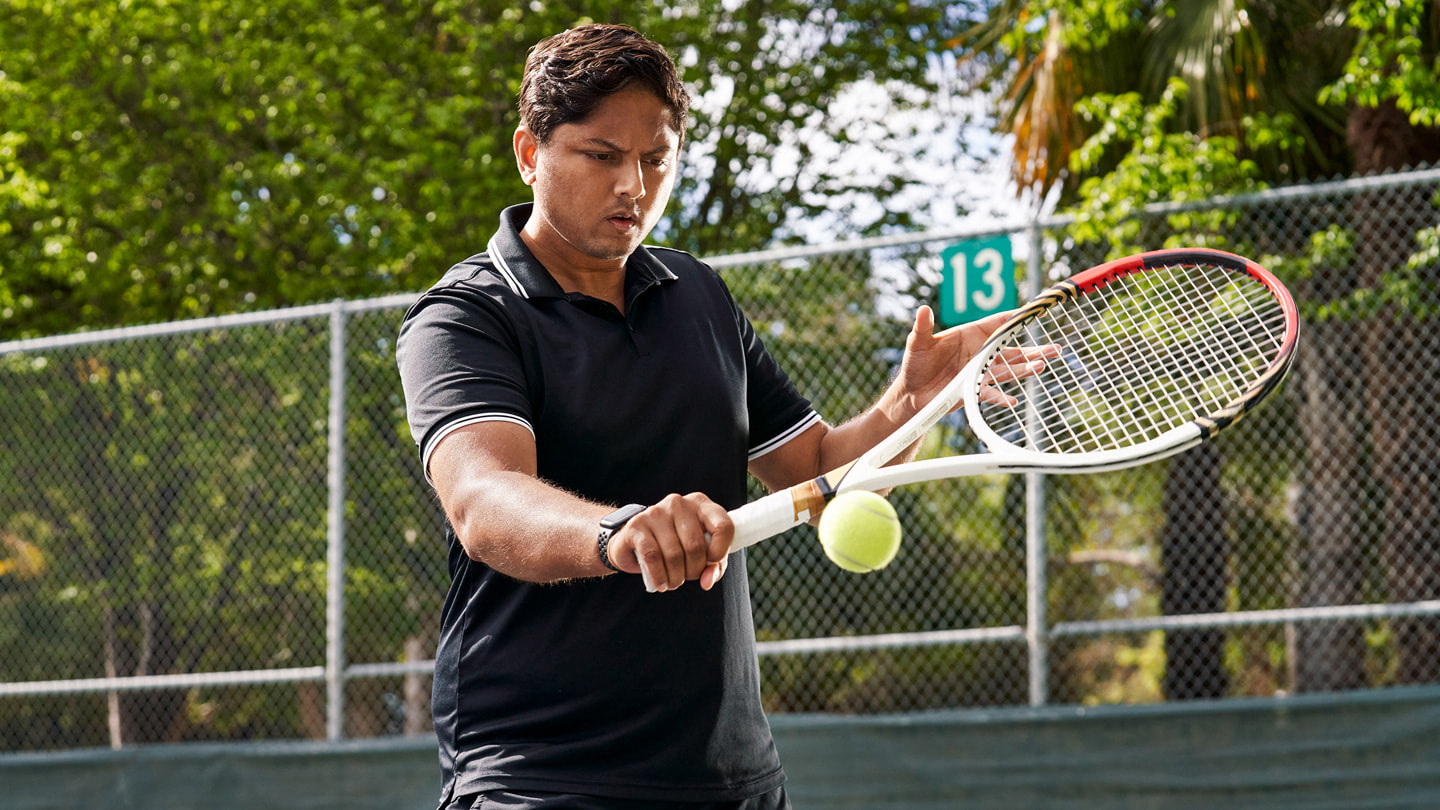 Sahai le da un golpe de revés a una pelota de tenis en la cancha.