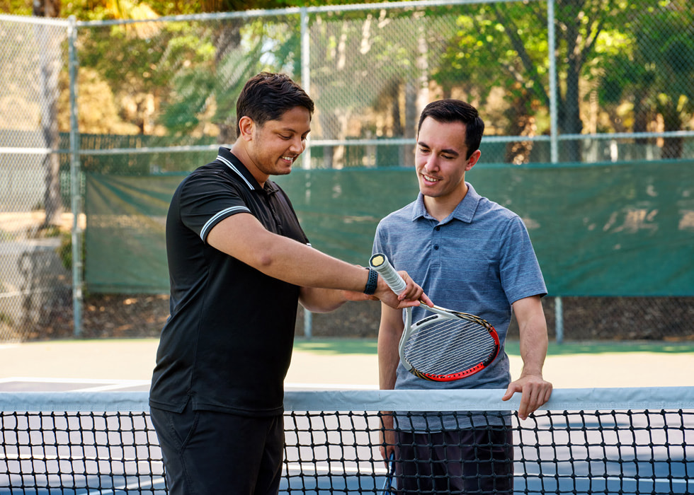 Sahai 在球場上向另一位網球選手展示他的 Apple Watch。