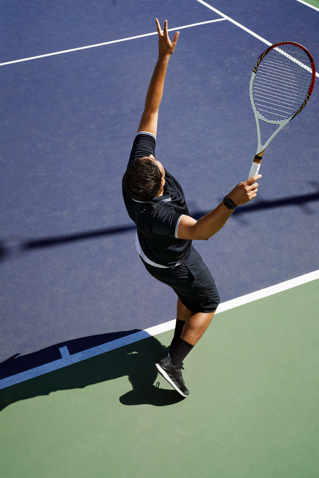 รูปภาพเหนือหัวที่แสดงให้เห็น Swupnil Sahai กำลังถือไม้เทนนิสในมือ และอยู่ระหว่างง้างมือเสิร์ฟลูกในสนามเทนนิส
