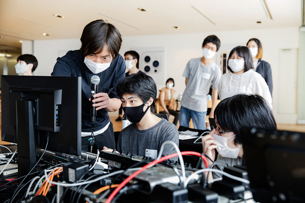 Voluntário da Apple segura um microfone ajuda no programa Creative Studios em Tóquio com integrantes do Sankakusha.
