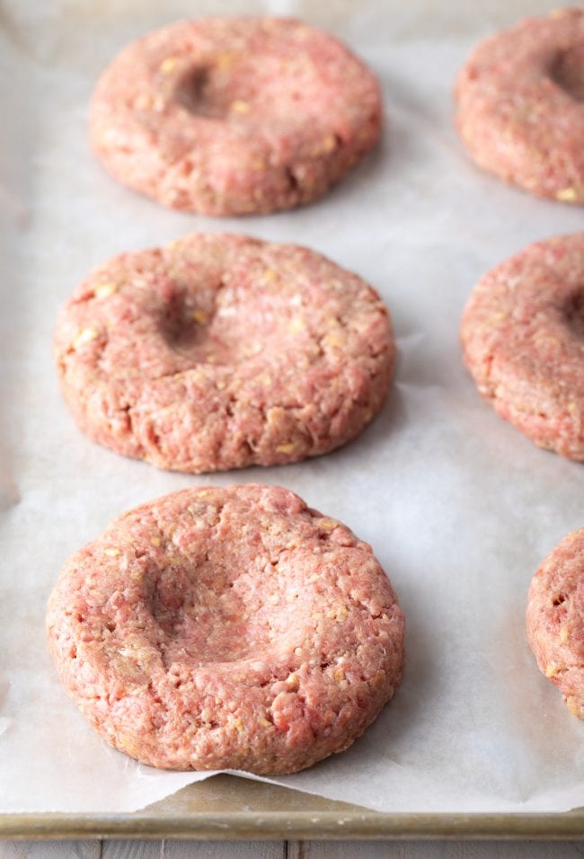 Hamburger patties with dents on top before being cooked. 