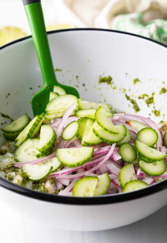 Adding cucumber slices to the bowl.