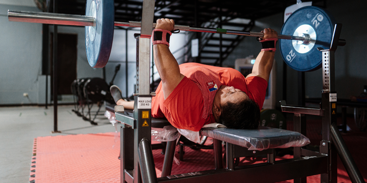 a fat person in an orange shirt benchpressing a barbell