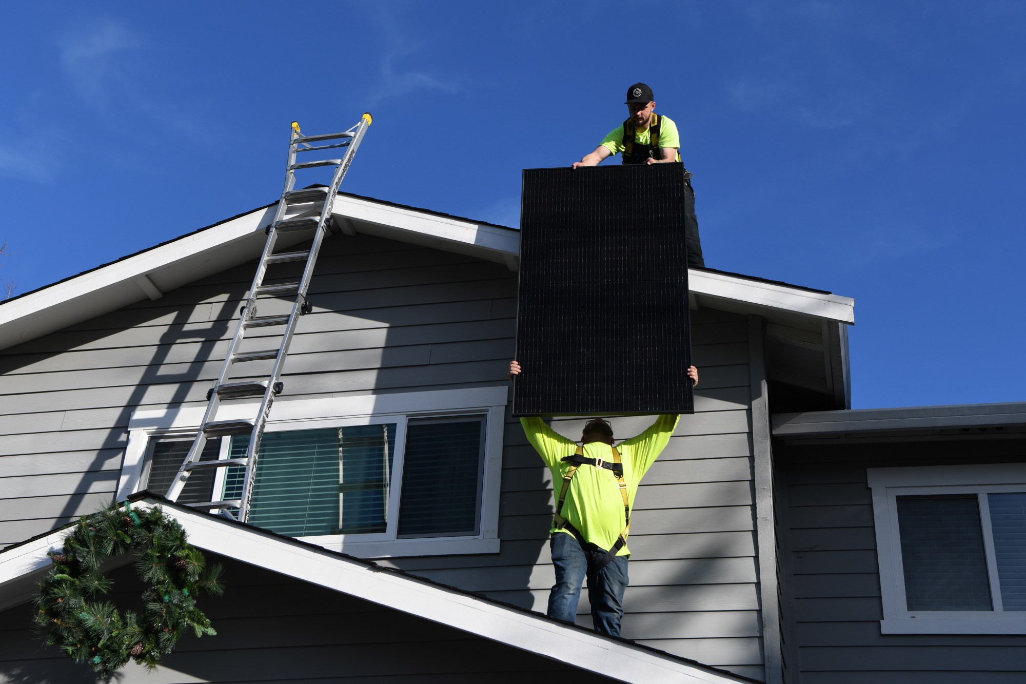 Corda Solar employee Brad Alvey, bottom, hands a solar panel to Brendan Baumgartner while installing solar panels at a home in Danville, Calif., on Thursday, Dec. 21, 2023. The California Public Utilities Commission will significantly cut the payments rooftop-solar owners get for selling their excess power back onto the grid. (Jose Carlos Fajardo/Bay Area News Group)