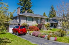 Red car parked in front of a suburban home