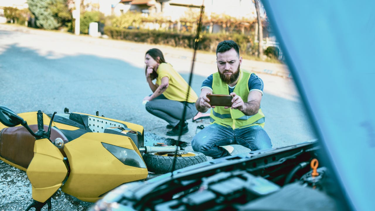 A consultant takes a photo of the aftermath from an accident with his smartphone.