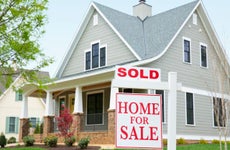 How to sell your house for cash - gray suburban home with brick front porch and "sold" sign in front yard