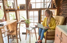 Woman takes notes while working on laptop.