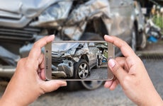 Man taking a picture of the damage on his car