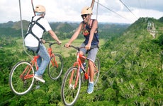 Two men biking on ziplines