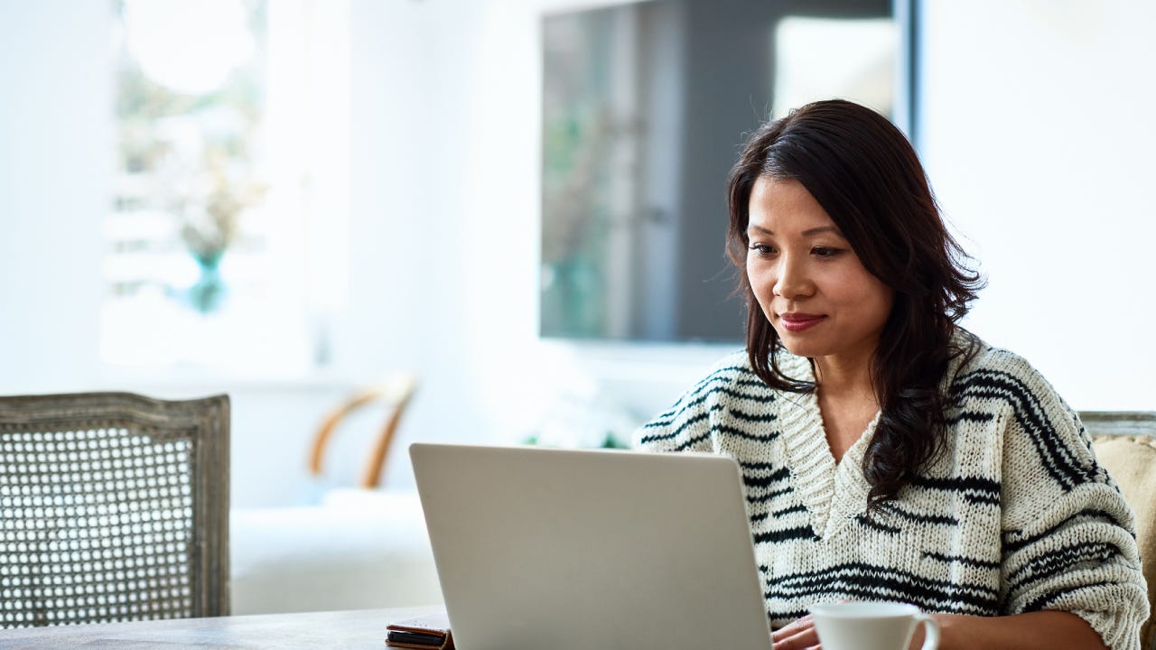 A woman sits in front of her laptop looking at her insurance and finance information