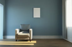 A shot of an empty living room with a blue wall and a white chair.