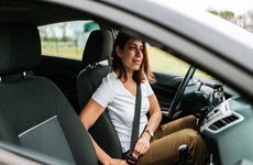 woman in car putting on seat belt