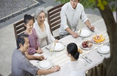 Extended Asian family sitting together outdoors enjoying a meal.