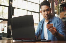 Man sitting at desk with laptop and credit card